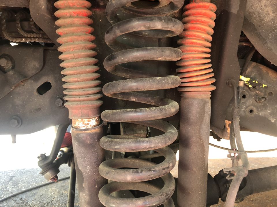 Close-up of front suspension with coil springs and red-booted shocks