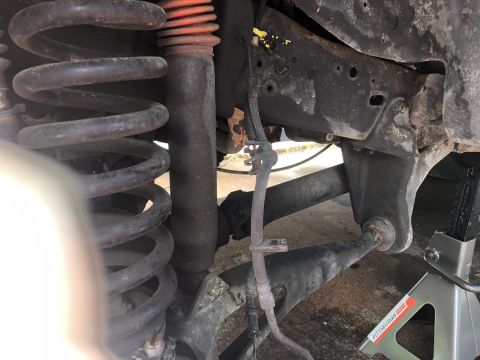 1995 Ford Bronco - Vehicle suspension components including a coil spring and shock absorber are shown, with a jack stand providing support.