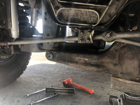 1995 Ford Bronco - Tools and suspension parts are laid out on the ground, suggesting maintenance or repair work on a vehicle's undercarriage.