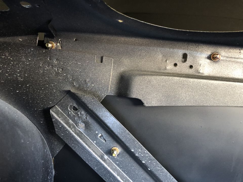 Close-up of dark gray painted inner body panel and bracket with bolts