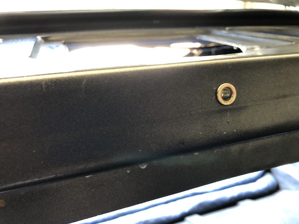 Close-up of black painted metal sill or rocker panel with rubber grommet