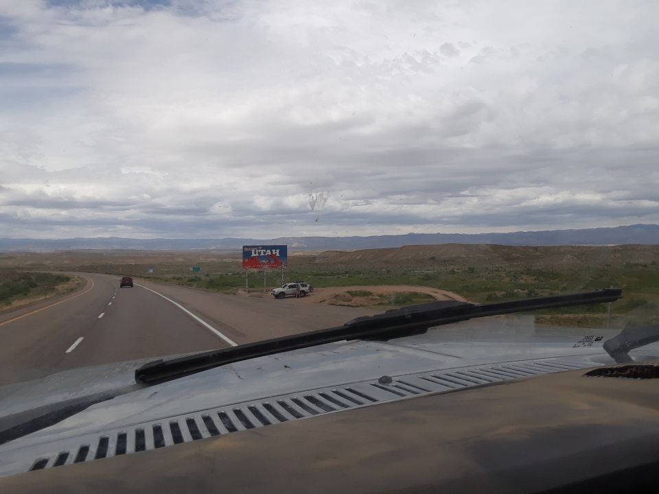 Highway sign for Utah with two vehicles parked nearby, seen from inside a vehicle