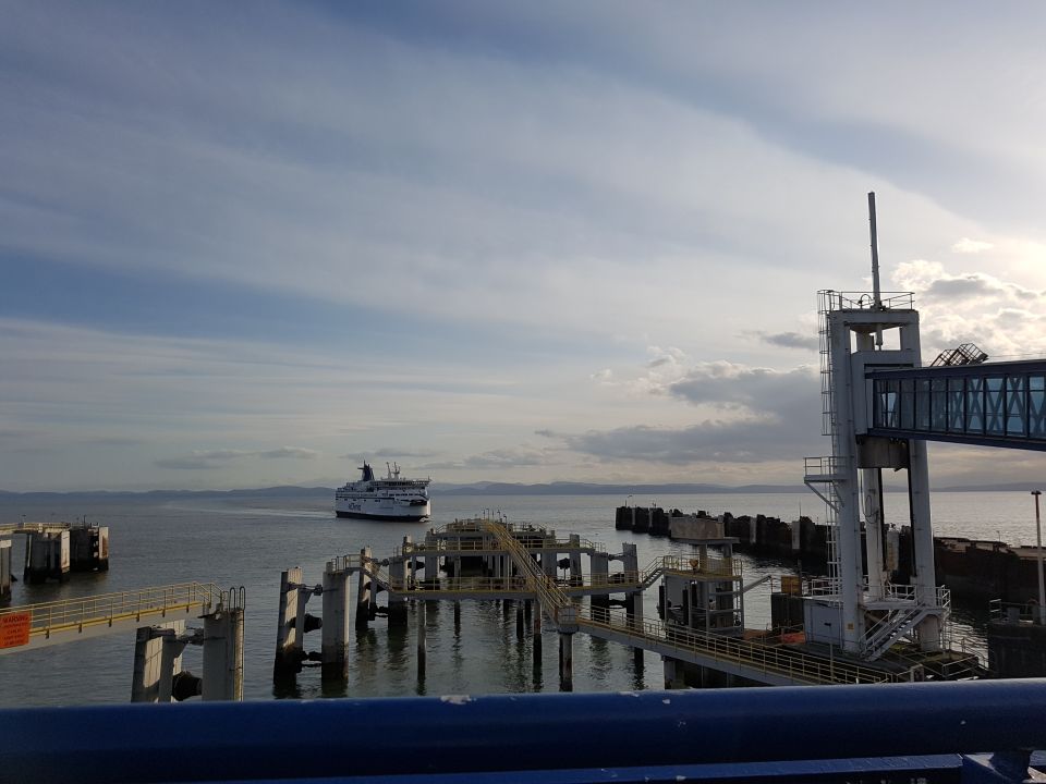 Ferry boat sailing near a dock with a pedestrian walkway.