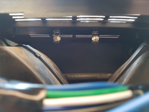 1978 Ford Bronco - A close-up view shows two metal bolts with nuts securing a bracket to a dark surface, with the curved tops of two vehicle components visibl…