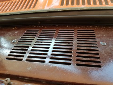 1978 Ford Bronco - A close-up, angled view shows a brown metal vent grille with horizontal slots. The grille is mounted on a surface that appears to be part o…