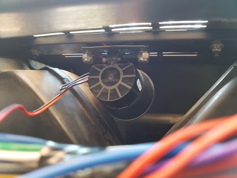 1978 Ford Bronco - A black Directed 514L siren is mounted with bolts to a metal bracket above a dark plastic component. Wires in red, black, and blue are conn…