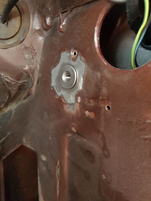 1978 Ford Bronco - A close-up view shows a threaded nut installed on a rusty metal surface, likely part of a vehicle's chassis or firewall. The surrounding ar…
