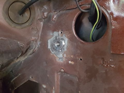 1978 Ford Bronco - A close-up view of a metal surface with a newly welded threaded nut. Wires are visible entering a circular opening on the right.