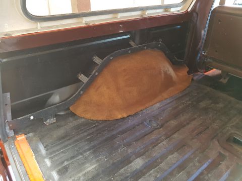 1978 Ford Bronco - The interior cargo area of a classic SUV, likely a Ford Bronco, shows the wheel well covered with brown carpet and the metal floor with vis…
