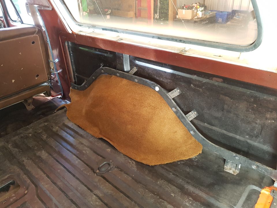 Interior of a vehicle cargo area with brown carpet on side panel and metal floor.