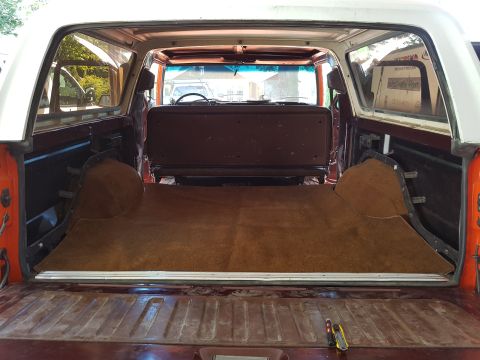 1978 Ford Bronco - The interior of a classic Ford Bronco shows a newly installed brown carpet covering the cargo area and the rear seat. The tailgate is open,…