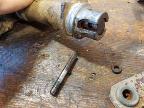 1978 Ford Bronco - A close-up view shows a disassembled metal part, possibly from a vehicle's engine or transmission, resting on a weathered wooden surface. A…