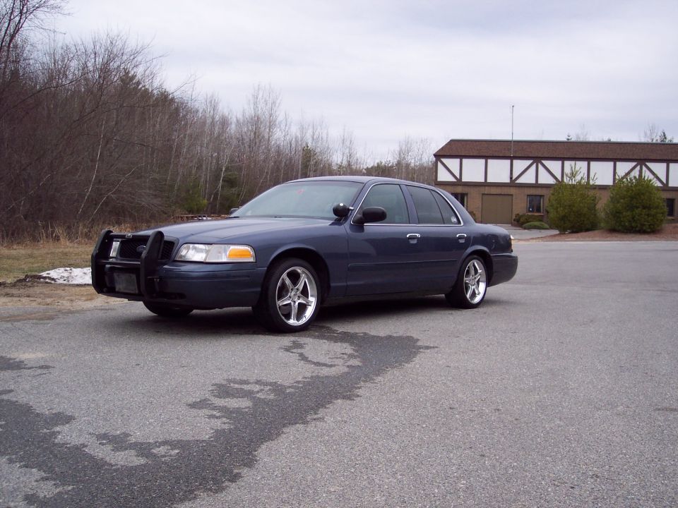 Dark blue 2001 Ford Crown Victoria with a push bar and aftermarket wheels parked on asphalt