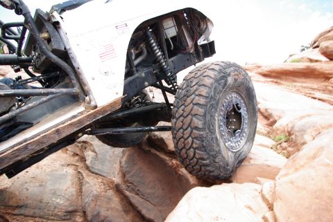 1995 Ford Bronco - A heavily modified off-road vehicle, likely a Ford Bronco, navigates a rocky terrain with its large, aggressive tires. The vehicle's chassi…