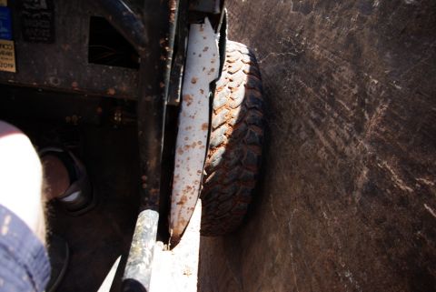 1995 Ford Bronco - A close-up view shows the muddy tire of a vehicle pressed against a rocky surface. The interior of the vehicle, including a roll cage and a…