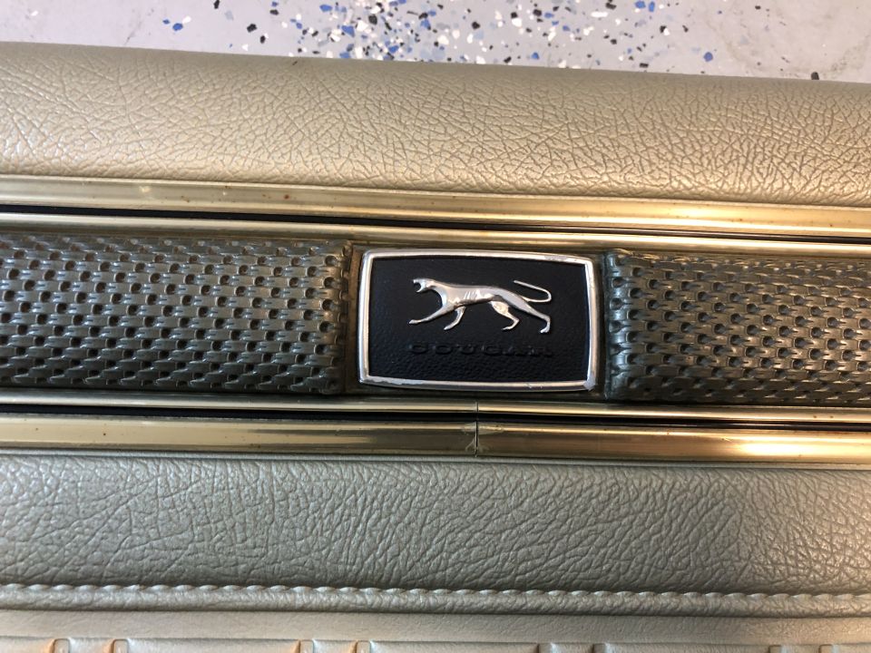 Close-up of a 1968 Mercury Cougar interior door panel with cougar emblem.