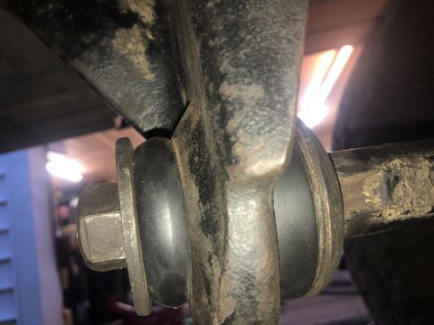 1995 Ford Bronco - A close-up view shows a suspension component with a large hex bolt and rubber bushing securing it to a metal bracket. The surrounding metal…