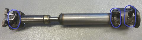 1995 Ford Bronco - A driveshaft with two universal joints is shown, with blue circles highlighting the universal joints at each end. A bearing is visible in t…