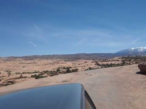 1985 Ford Bronco - A vast desert landscape unfolds under a clear blue sky, with a tranquil body of water reflecting the scene.