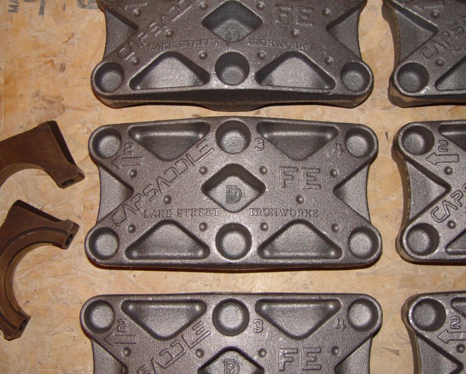 Cast iron Capsaddles FE main cap girdles stamped Lake Street Ironworks on a workbench