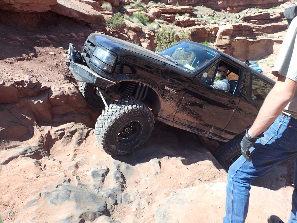 Black Ford Bronco off-roading on a steep, rocky trail.
