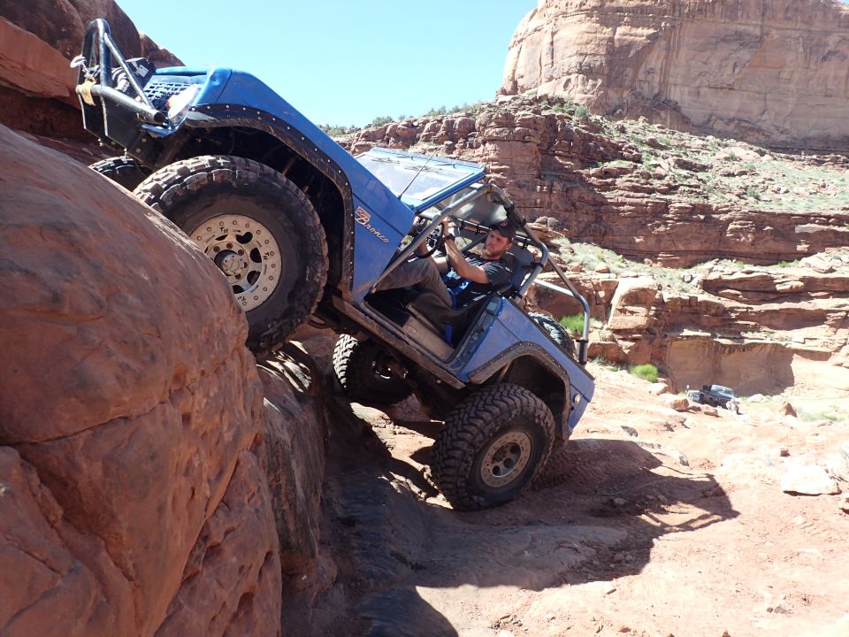 Blue Ford Bronco off-roading on a steep rocky trail.