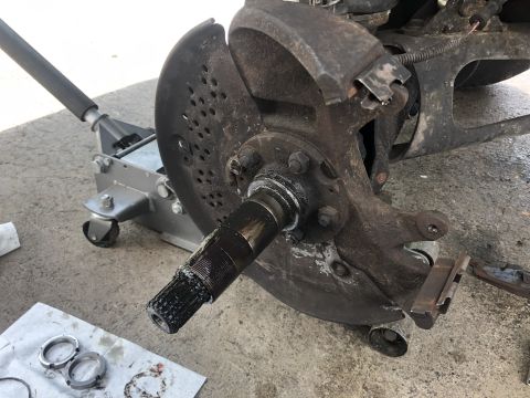 1995 Ford Bronco - A close-up view of a vehicle's front wheel hub assembly, showing the splined axle shaft covered in grease, a brake rotor shield, and part o…