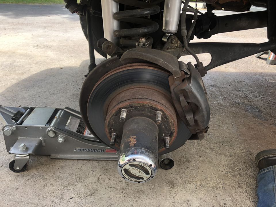1995 Ford Bronco front driver's side brake assembly with floor jack.