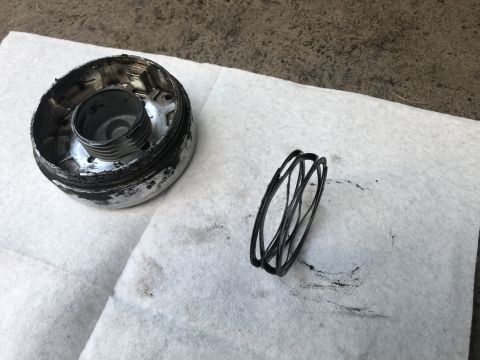 1995 Ford Bronco - A disassembled oil filter cap with a spring is shown on a white towel. The cap is metallic and appears to have black residue on its interio…