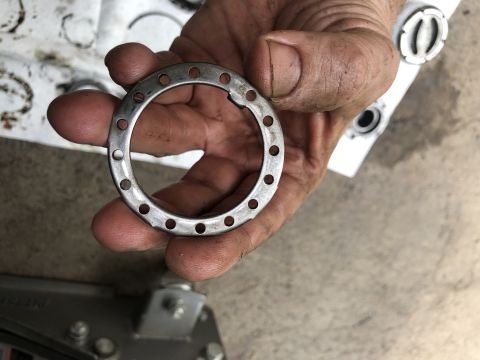 1995 Ford Bronco - A close-up shot shows a person's dirty hands holding a metal ring with multiple small holes around its circumference. In the background, ot…