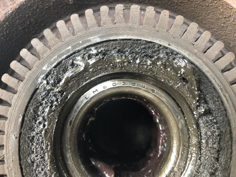 1995 Ford Bronco - A close-up view of a heavily greased and dirty wheel bearing assembly, possibly from a 1995 Ford Bronco. Visible stamped text on the bearin…
