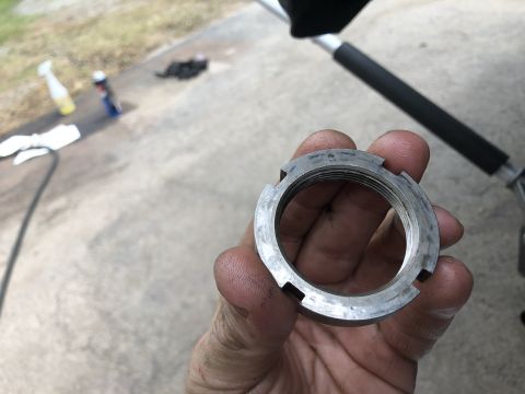 1995 Ford Bronco - A hand holds a metal locknut with internal threads and external notches. In the background, a black rubber grip is visible on a metal pole,…