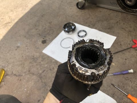 1995 Ford Bronco - A gloved hand holds a heavily greased and worn metal part with visible teeth and stamped text. Several other small metal parts and tools ar…