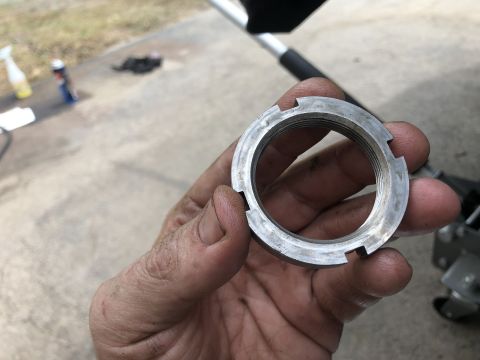 1995 Ford Bronco - A hand holds a metal castle nut with internal threads and four notches on the outer edge. The nut appears to be a component for a vehicle's…