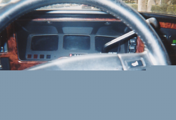 Steering wheel and digital instrument cluster behind woodgrain dashboard trim