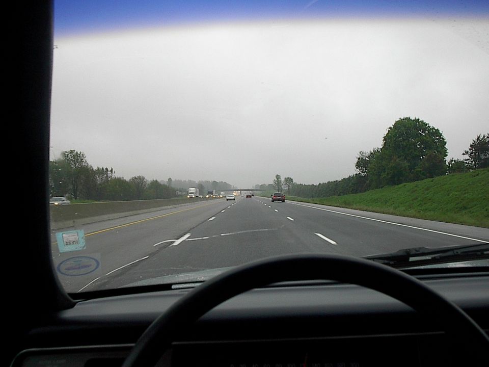 View from inside a car on a highway, showing the dashboard, steering wheel, and the road ahead.
