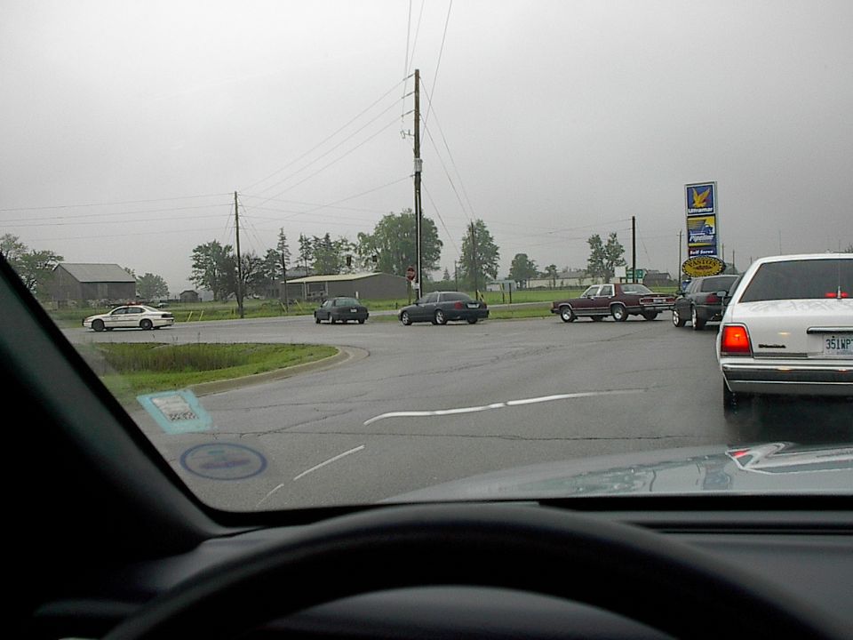 1985 Mercury Grand Marquis parked at a wet intersection.