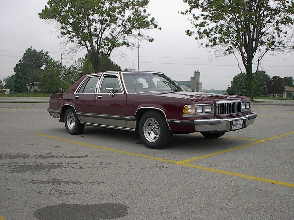 1985 Mercury Grand Marquis sedan, maroon color, parked in an asphalt lot.