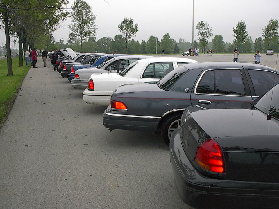 Several sedans parked in a line on an asphalt lot.
