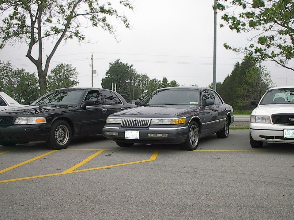Two Mercury Grand Marquis sedans parked side-by-side in a parking lot.