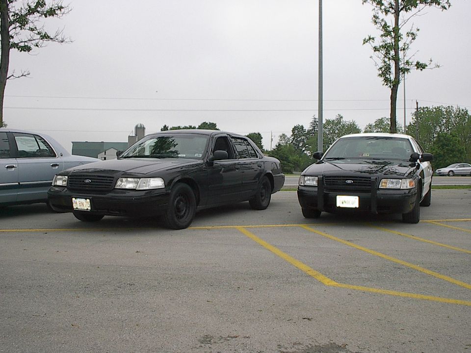 Two black sedans parked in a lot.