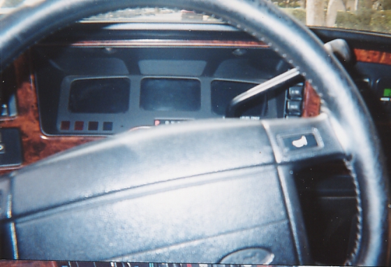 Interior dashboard and steering wheel of a Ford with woodgrain trim and digital-style gauge cluster