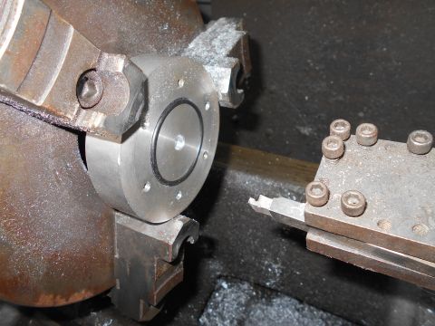 1992 Ford Bronco - A close-up view of a metalworking lathe with a workpiece held in the chuck and a cutting tool engaged. Metal shavings are visible around th…