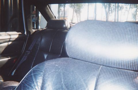 1991 Ford Taurus - The interior of a 1991 Ford Taurus, dark leather rear seats and patterned headrests.