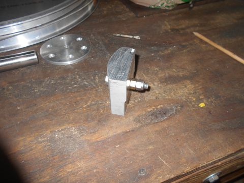 1992 Ford Bronco - A metal bracket with a bolt and nut attached is shown on a wooden workbench. Other metal parts and tools are visible in the background.
