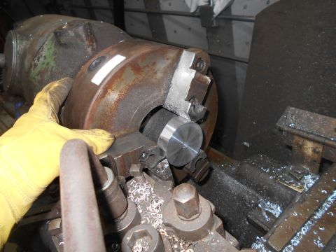 1992 Ford Bronco - A gloved hand is holding a metal workpiece against a lathe chuck. Metal shavings are visible on the machine.
