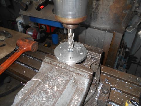 1992 Ford Bronco - A milling machine is being used to drill holes in a circular metal plate. Metal shavings are scattered across the machine's table and a rub…