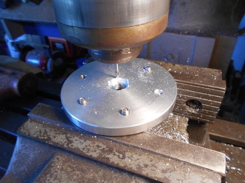 1992 Ford Bronco - A close-up view of a metal disc being machined on a milling machine. Metal shavings are visible on the workpiece and the machine bed.