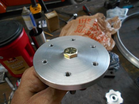 1992 Ford Bronco - A hand holds a circular aluminum part with a hex bolt in the center and several smaller holes around the perimeter. In the background, a re…