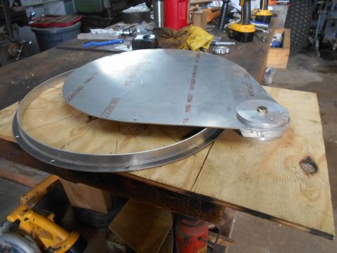 1992 Ford Bronco - A large, circular metal component with text stamped on it is resting on a wooden surface. A smaller, circular metal piece with a bolt is at…